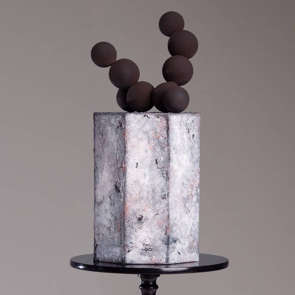 Pastel con efecto concreto y esferas de chocolate del curso Especial Texturas